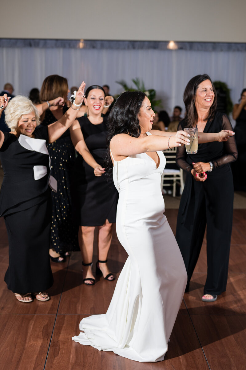 Bride dancing joyfully at the Emerald at Queensridge reception, surrounded by guests and glowing candlelight.