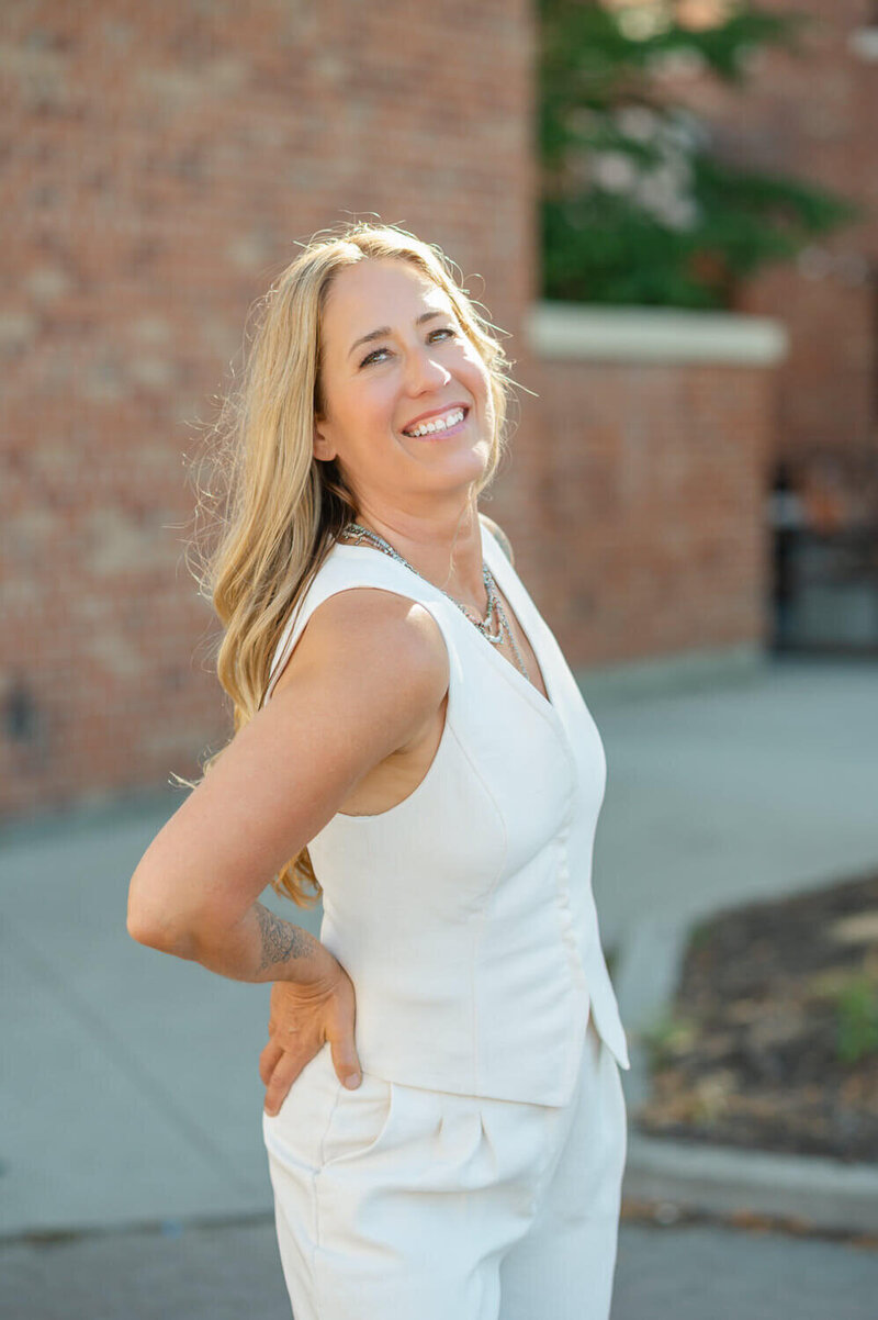 Portrait of a professional photographer wearing cream vest suit and smiling at the camera.