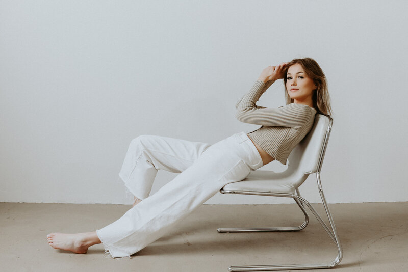 Girl sitting on white chair in studio