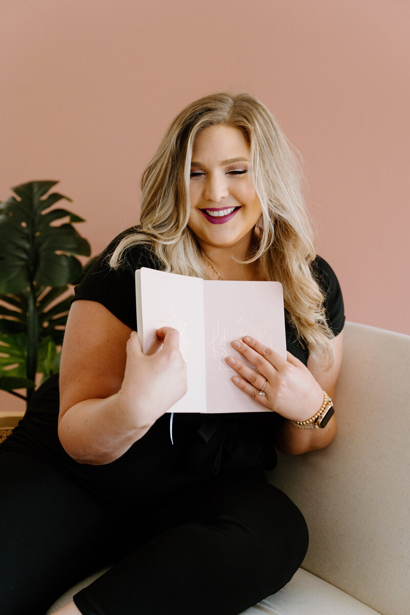 Portrait of smiling female brand owner holding light pink planner.