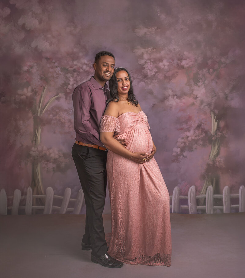 "Expecting couple in a loving embrace in a cherry blossom-themed studio maternity session in Ottawa"