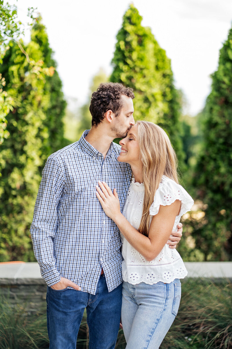 man kisses his fiancé on the forehead at JC Raulston Arboretum in Raleigh