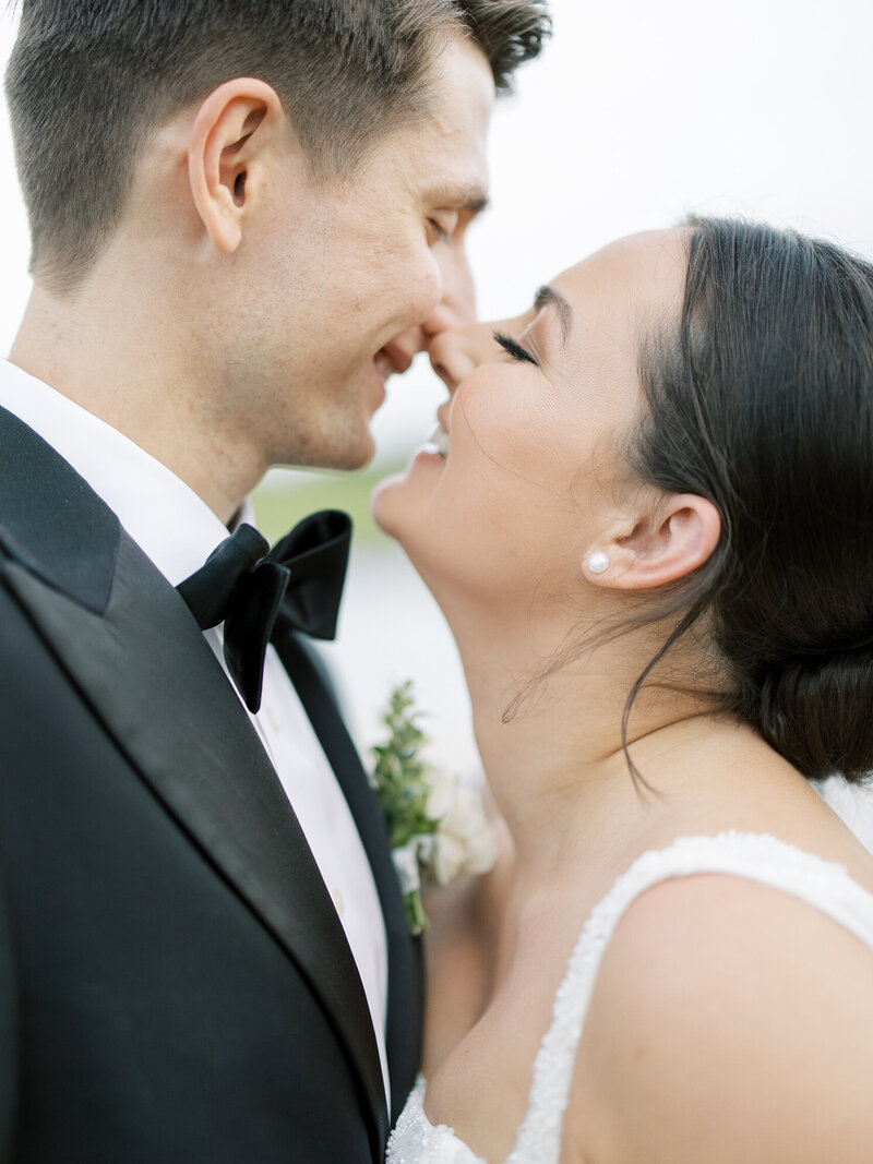 A close up of a joyful bride and groom right before they kiss