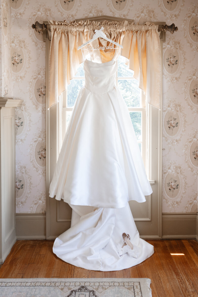 Full view of the bride’s wedding dress hanging in natural light at the historic Felt Estate