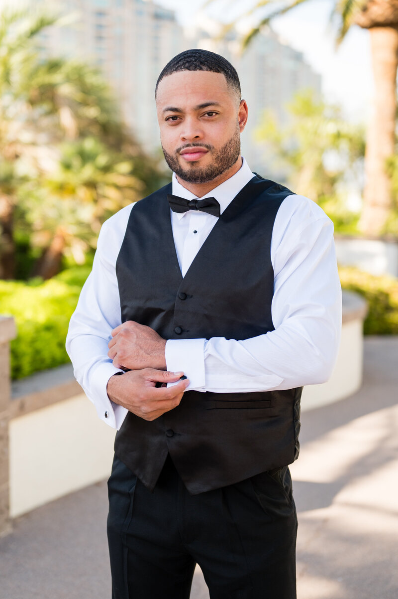 Groom adjusting cufflinks in classic black tuxedo from Men’s Warehouse at Emerald at Queensridge.