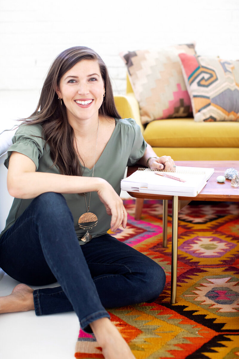 Birds-eye-view of a woman  with medium to dark skin tone typing on a laptop on a wooden table