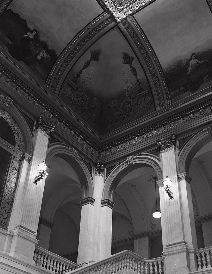 Ornate interior featuring large arches, detailed moldings, and a decorated ceiling. A grand staircase leads upwards; elegant and historic Ohio ambiance.