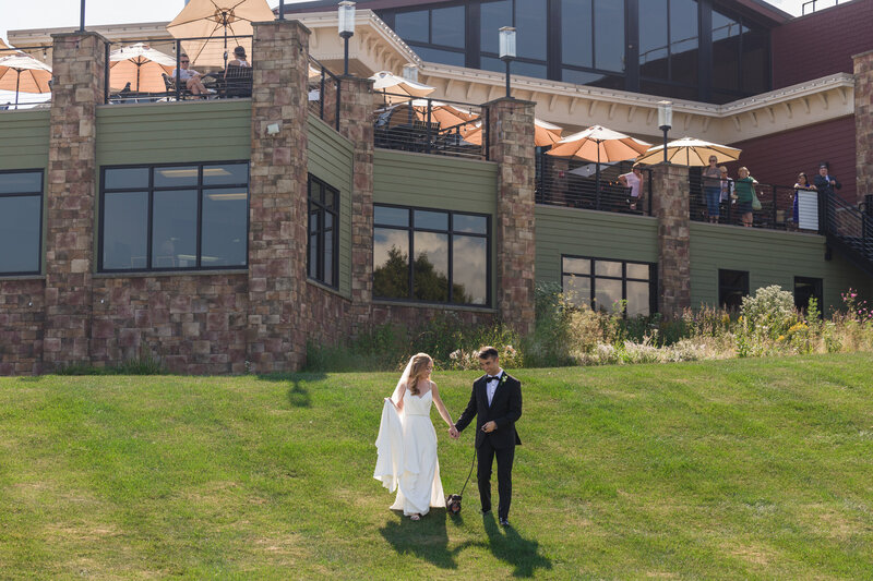 Couple walking their dog away from Blue Mountain Resort, with the wedding venue visible in the background.