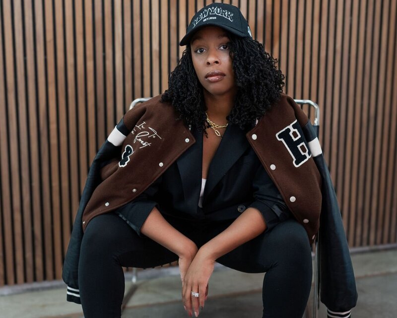 Meet your challenge host- Latesha—Your Marketing & Lead Generation Strategist. She's leaning against a wall in a brown body suit, slacks, hand in her pocket, apple watch, smiling with red lipstick on. 