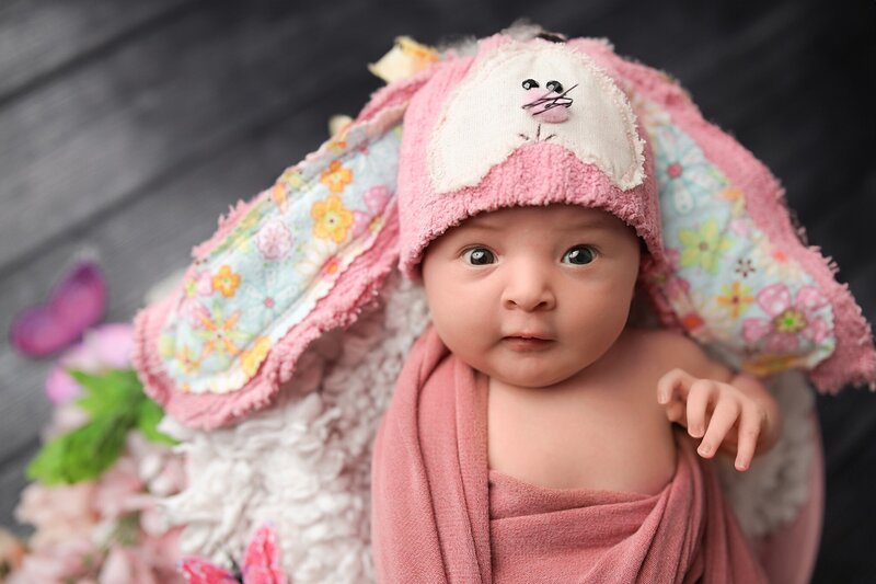 Sleeping newborn on pink blanket smiling