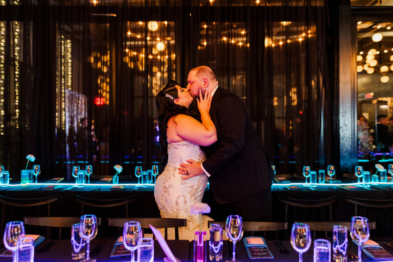 bide and groom holding each other and sharing a kiss inside of their wedding venue.