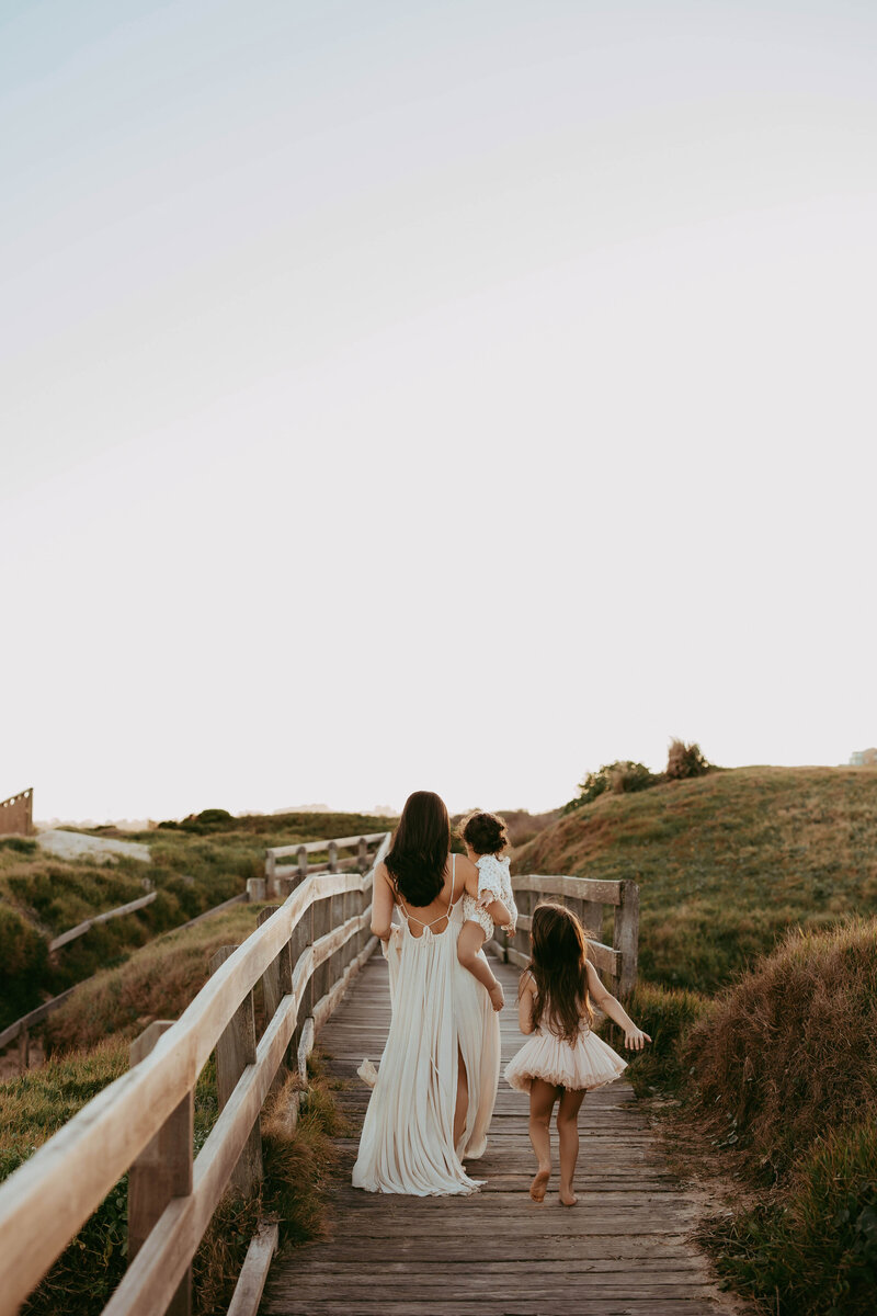 Family walking together along coastal track in golden light, captured by Sydney family photographer Sophie Lea.