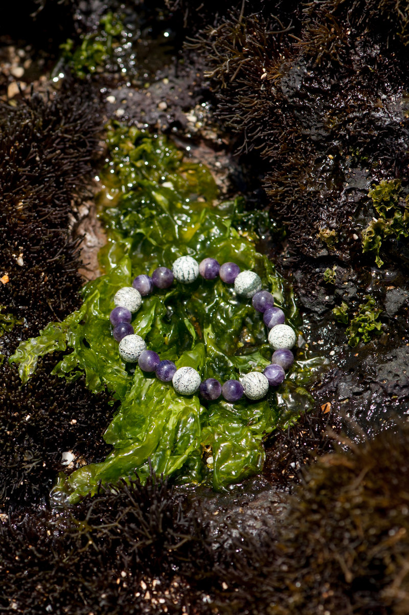 A Moss Agate and Amethyst Bracelet laying on Moss.