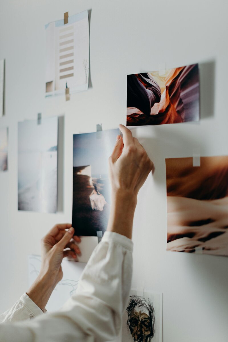 Woman hangin printed pictures with tape on wall