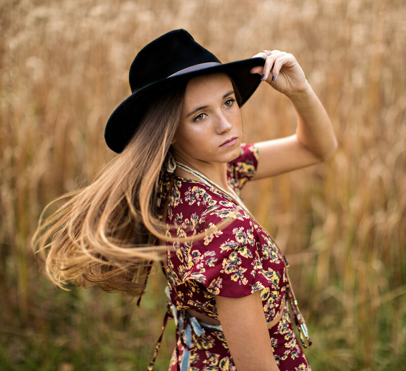 This Cleveland senior holds her hat while in a field.