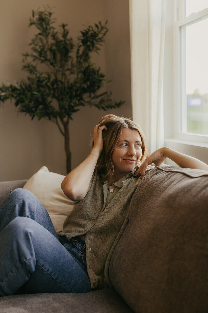 Minnesota wedding and lifestyle photographer looks out the window of her home as she relaxes on her couch