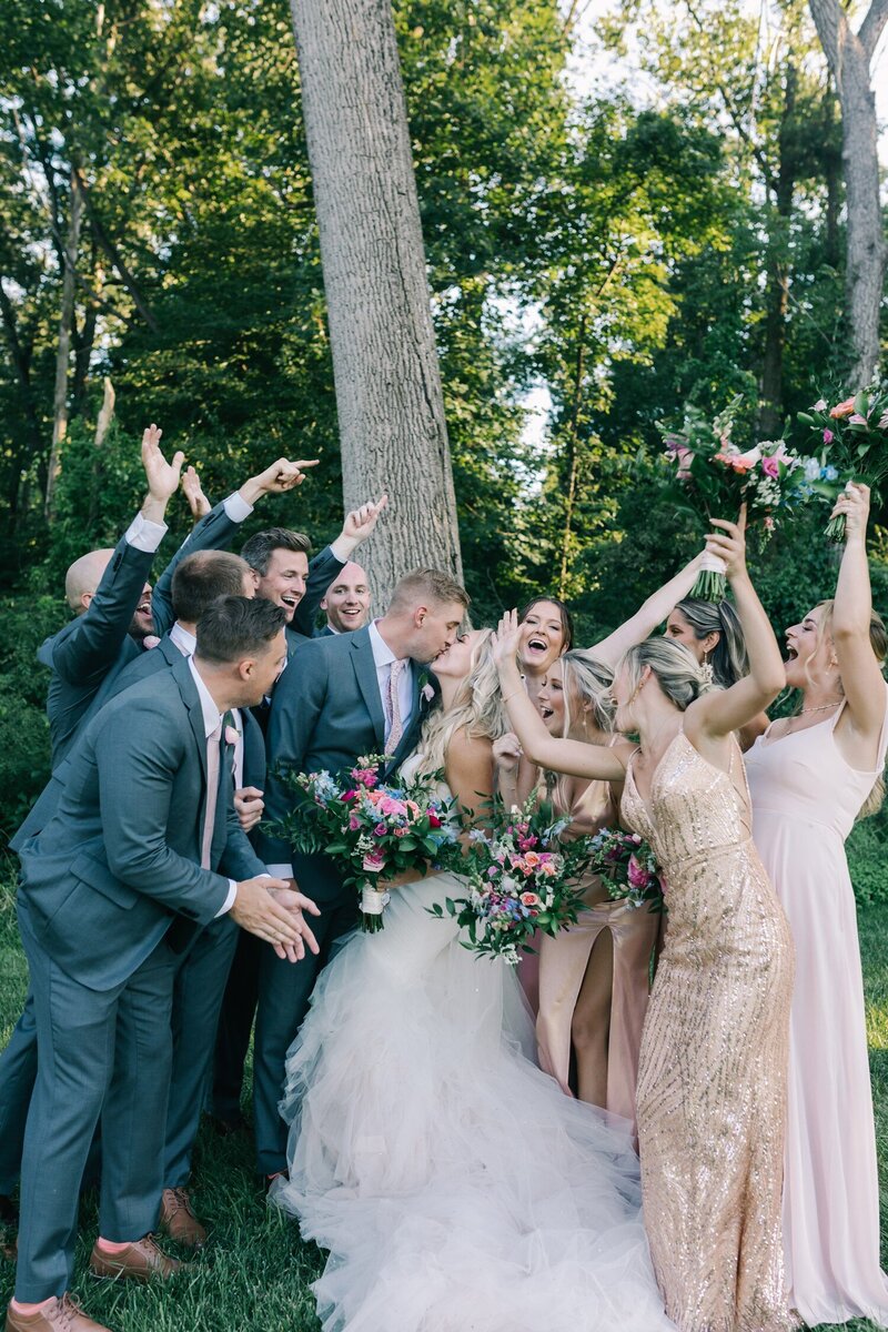 Wedding Party cheering while bride and groom kiss