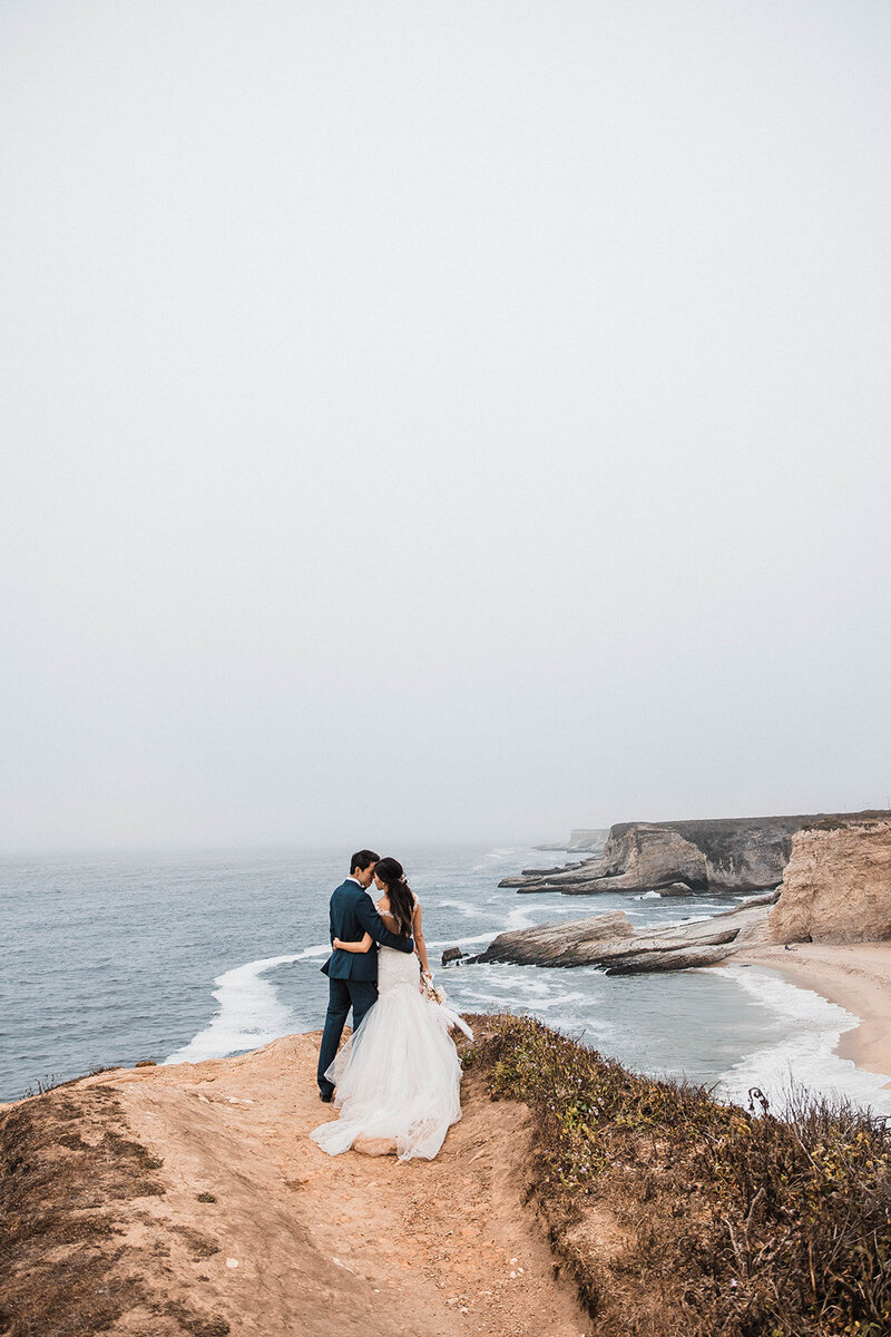 A couple enjoying their romantic coastal elopement in Santa Cruz, California. Captured by a leading California elopement photographer, this image highlights the stunning ocean views and intimate moments of their special day.