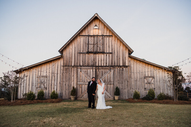 Bride & Groom posing in front of barn at Barn at Acord Ridge wedding venue in Toomsboro, GA. Savannah wedding photos.
