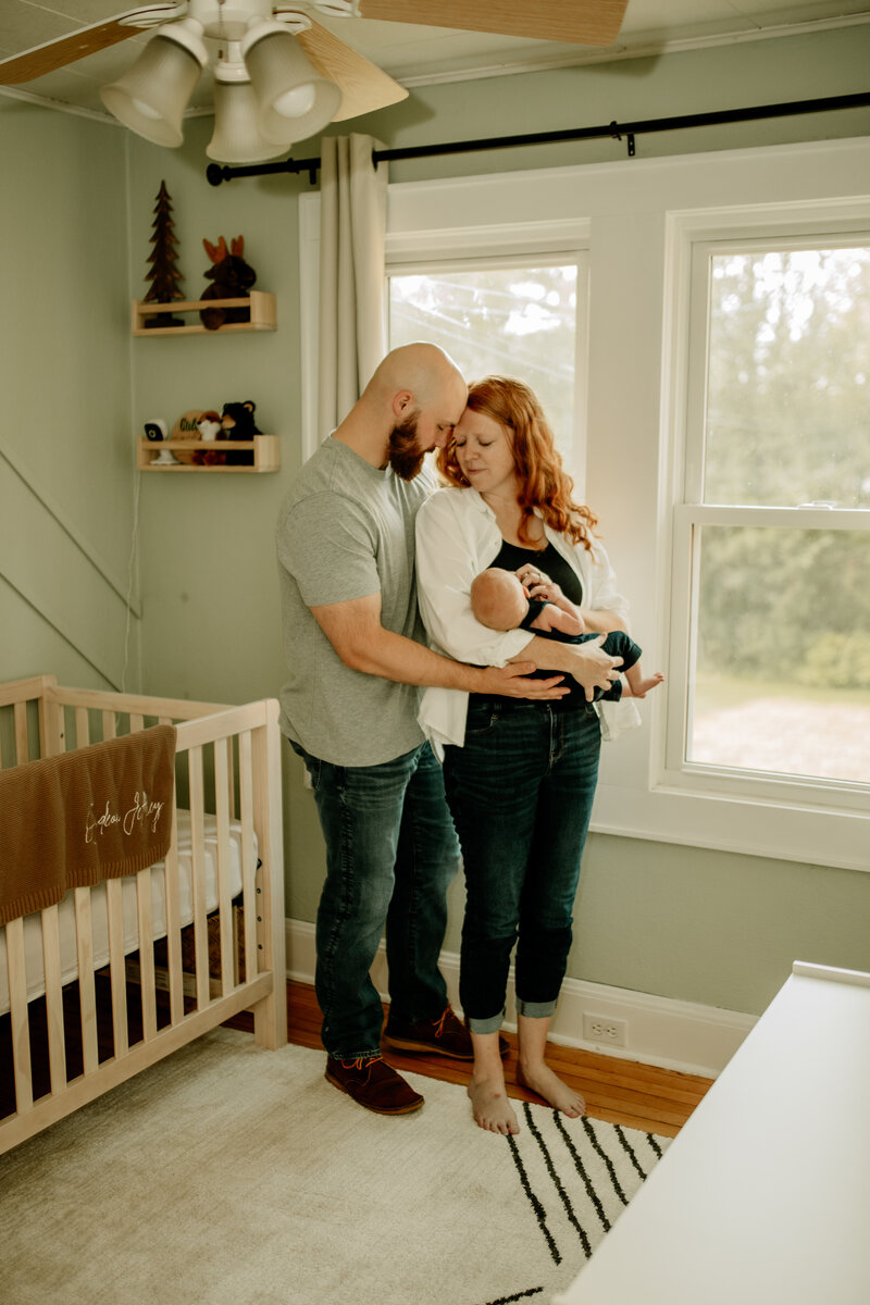 A new family of three holds their baby boy in his woodland nursery during a cozy Minnesota in-home newborn session.