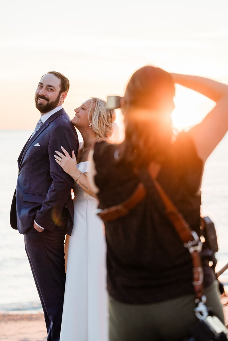 A married couple smiling as a photographer takes their picture