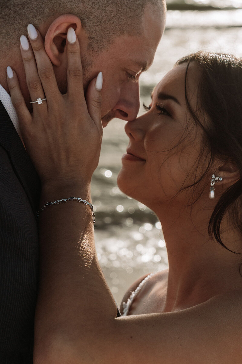close up of couple hands on face showing engagement ring