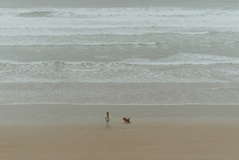 girl and dog running on the beach at the oregon coast
