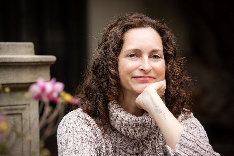 A person smiling and resting her chin on her hand.