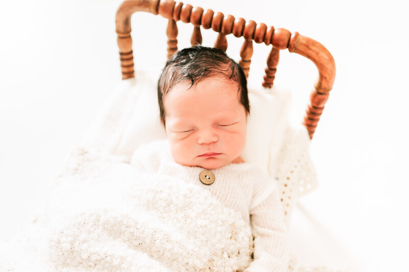 close up of baby boy sleeping in wood crib in all white Springfield MO newborn photography studio