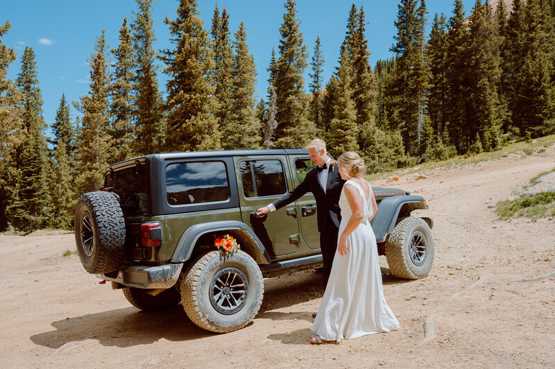 Bride and groom with Jeep on mountain road
