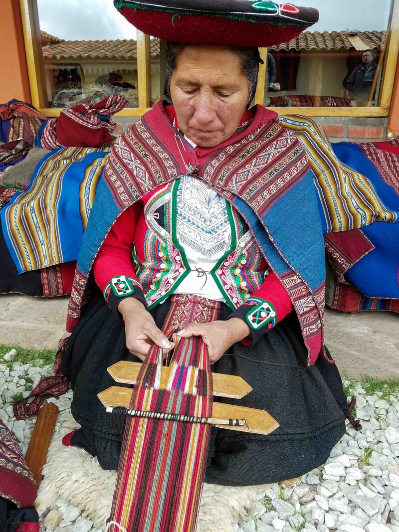 A woman wearing traditional dress and weaving on a backstrap loom in Peru's Sacred Valley ©Stephanie Dosch | theViatrix Luxury Travel