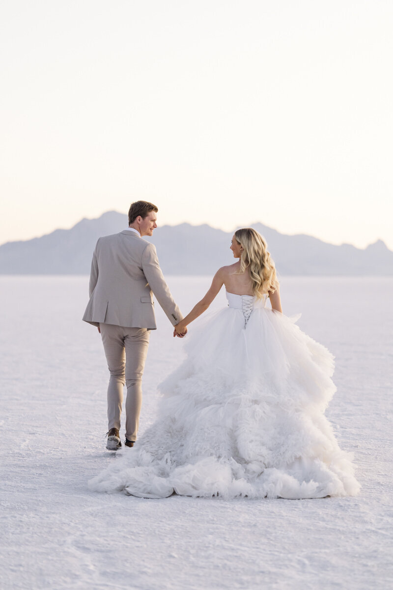 bride and groom holding hands while facing a mountain range