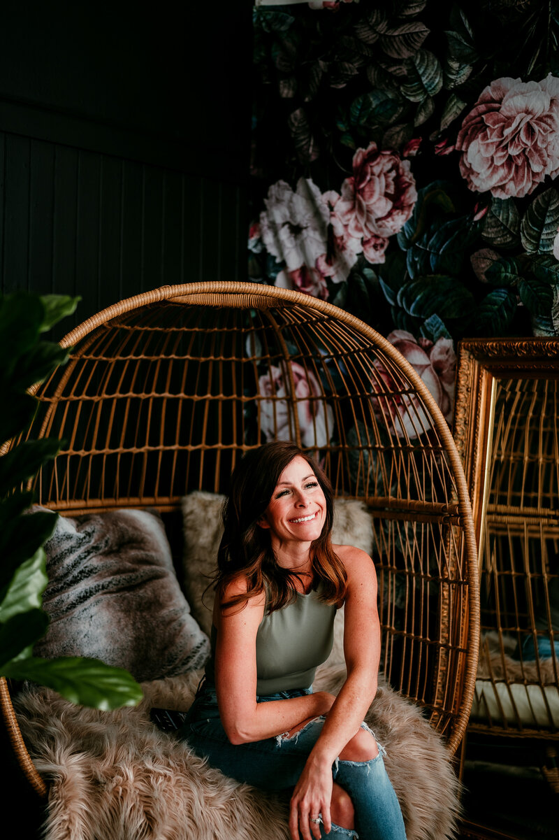 Confident woman smiling in a cozy boho-style egg chair, representing self-love, personal growth, and dating confidence tips.