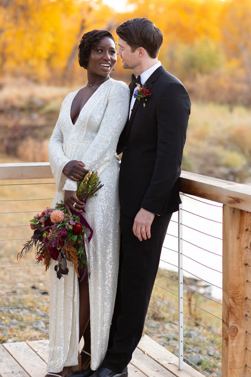 Bride and groom on deck overlooking river at Wyoming outdoor wedding venue