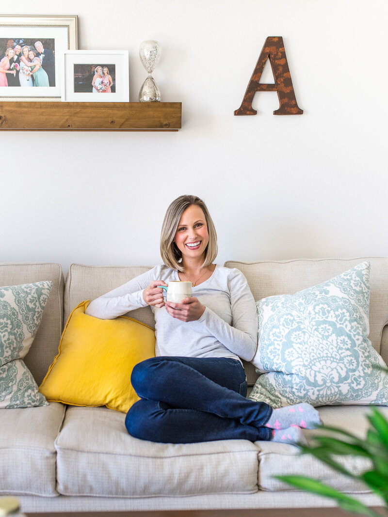 Headshot of Amanda Miller sitting on the sofa with a mug.