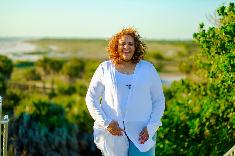 Certified life coach Claudine Martinell, dressed in white and basking in the sun, inviting you to a journey of transformation and empowerment.