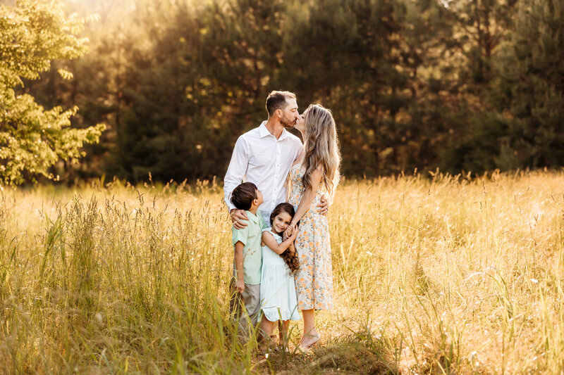 Family of four in a field during golden hour.