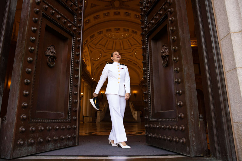 brunette Midshipman in  whites uniform and heels struts through doors of bancroft hall at Naval Academy