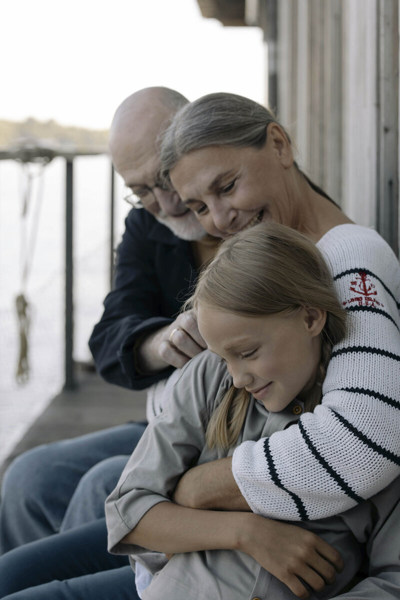Grandparents hugging their granddaughter