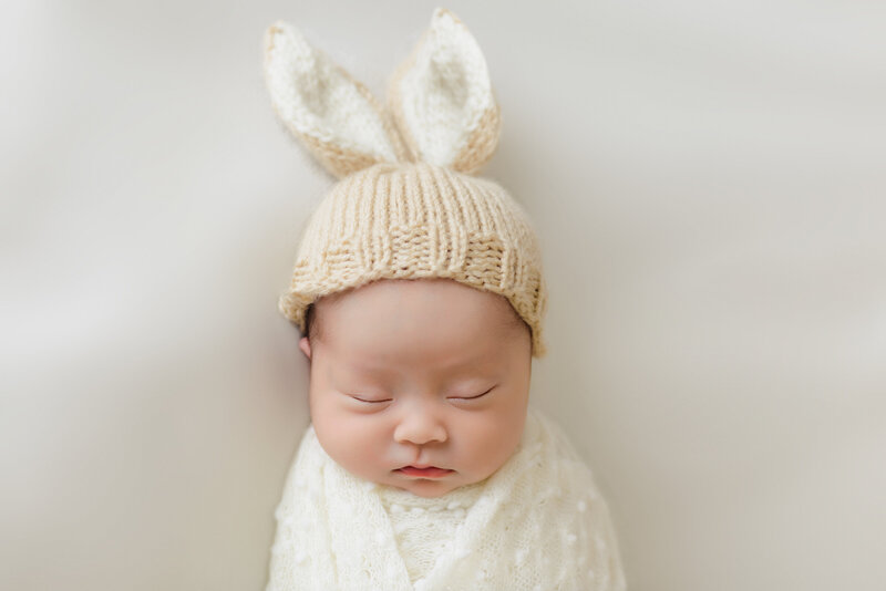 San diego newborn photographer, a newborn baby sleeping and swaddled with a bunny hat