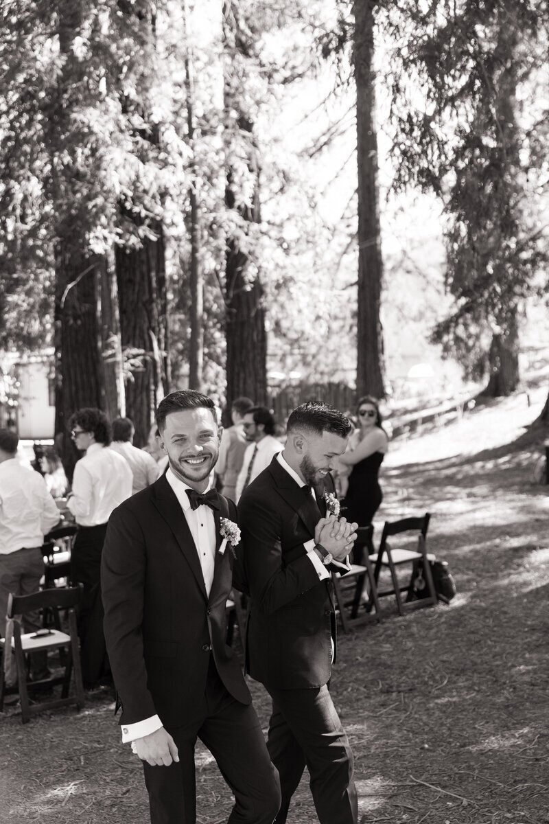 Same-sex couples walk hand in hand back down isle after outdoor Redwood ceremony in California by destination wedding photographer Erica Rochelle Photography