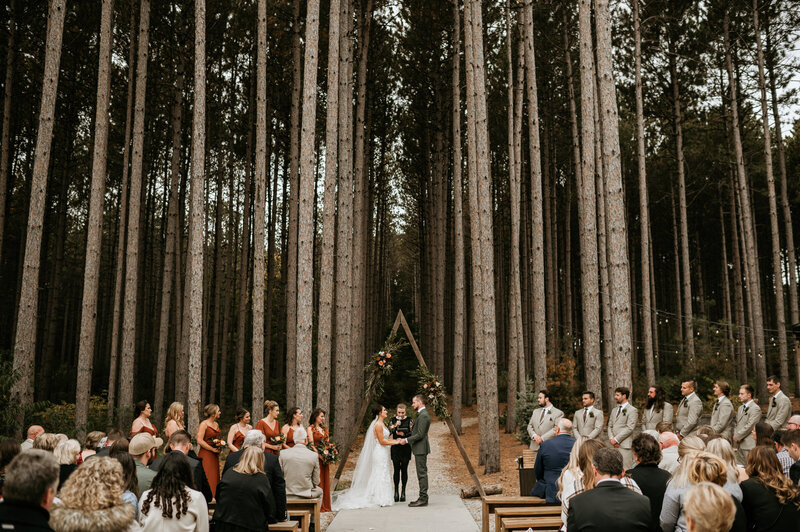 Bride and groom exchanging vows in a pine forest during their luxury wedding ceremony in Minnesota