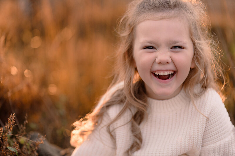 Portret van meisje met een stralende lach en lange haren tijdens een gezinsshoot in Apeldoorn