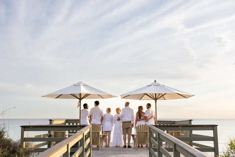 A family standing at the edge of a pier looking out towards the water