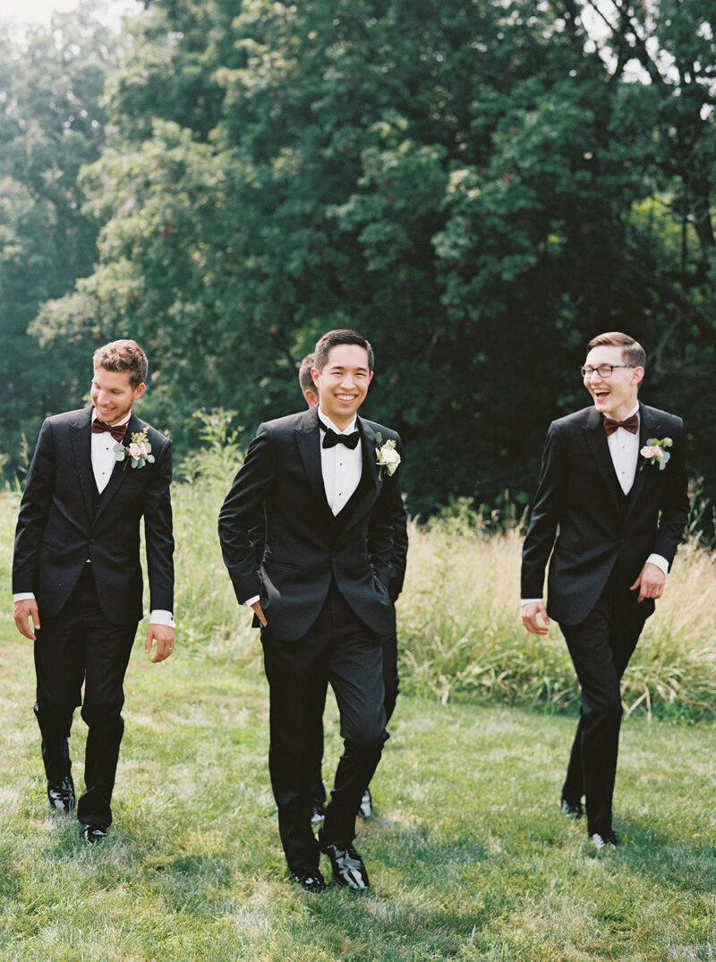 groomsmen walking through Kentucky field smiling