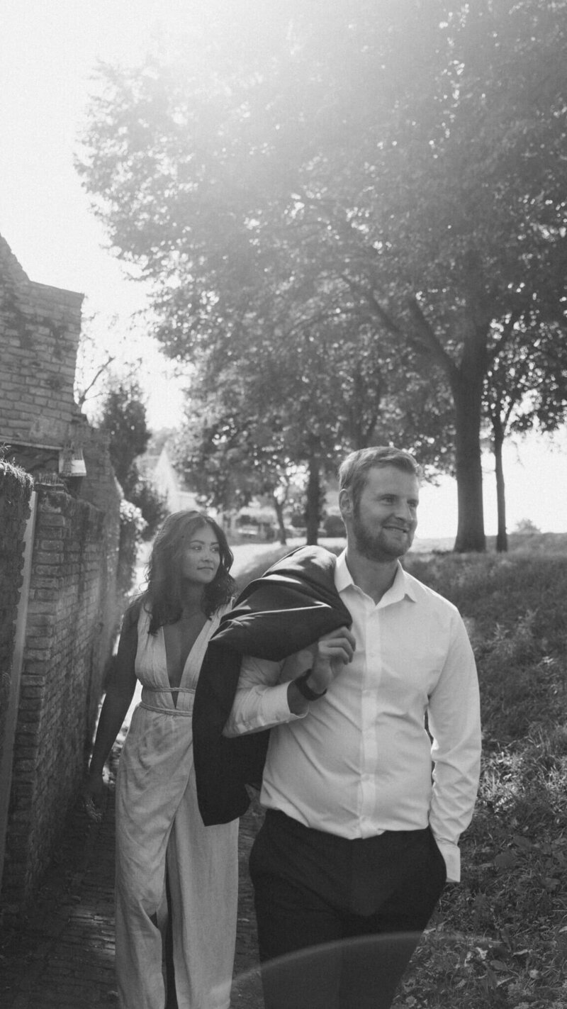 Een man en een vrouw zitten op een bankje. De man zit lager dan de vrouw waardoor er een hoogteverschil is wat de foto diepte geeft. Beiden kijken ze een andere richting op.