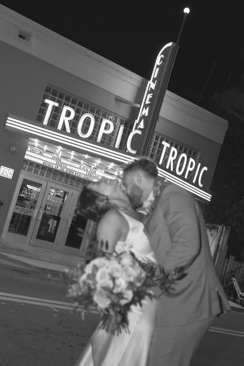 bride and groom embracing while standing on the beach