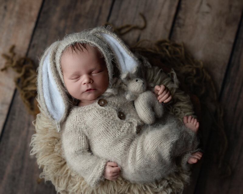 Rustic newborn portrait in a fluffy hand-knit bunny outfit with coordinating toy.