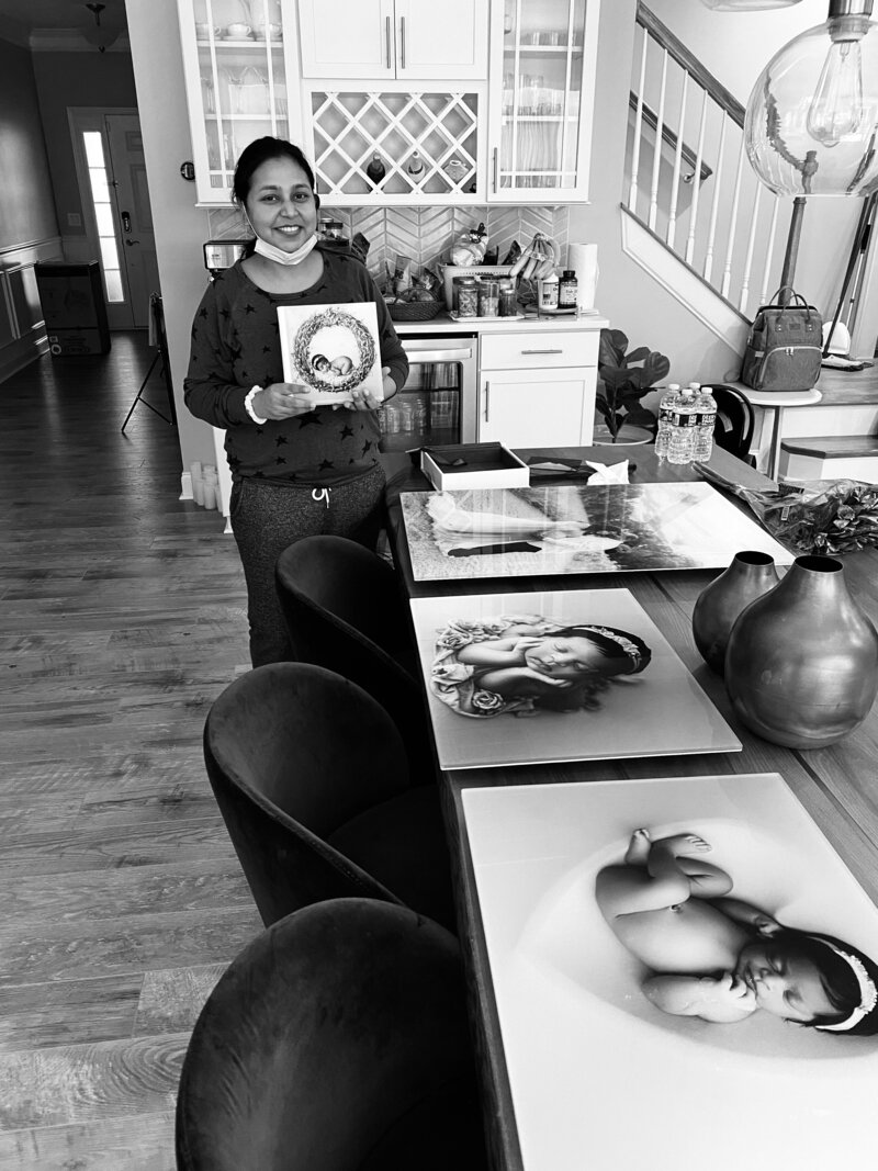 Mom holding newborn baby posing with a photo album and wall art