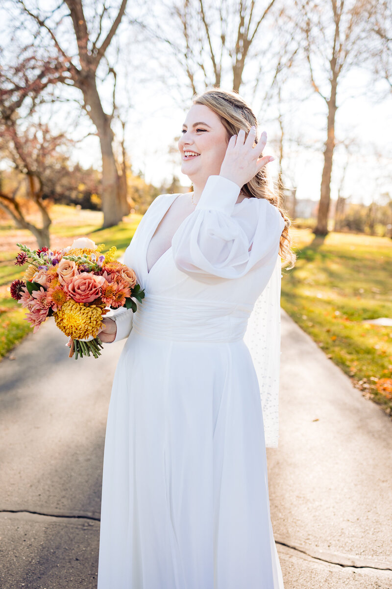 A bride brushes her hair back while holding her bouquet at Cornman Farms in Michigan